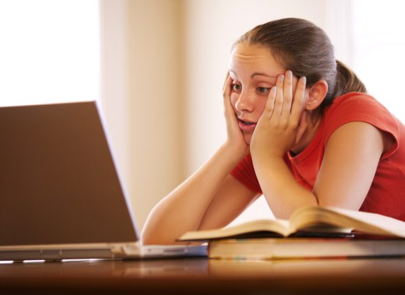 Teenage girl with laptop doing homework
