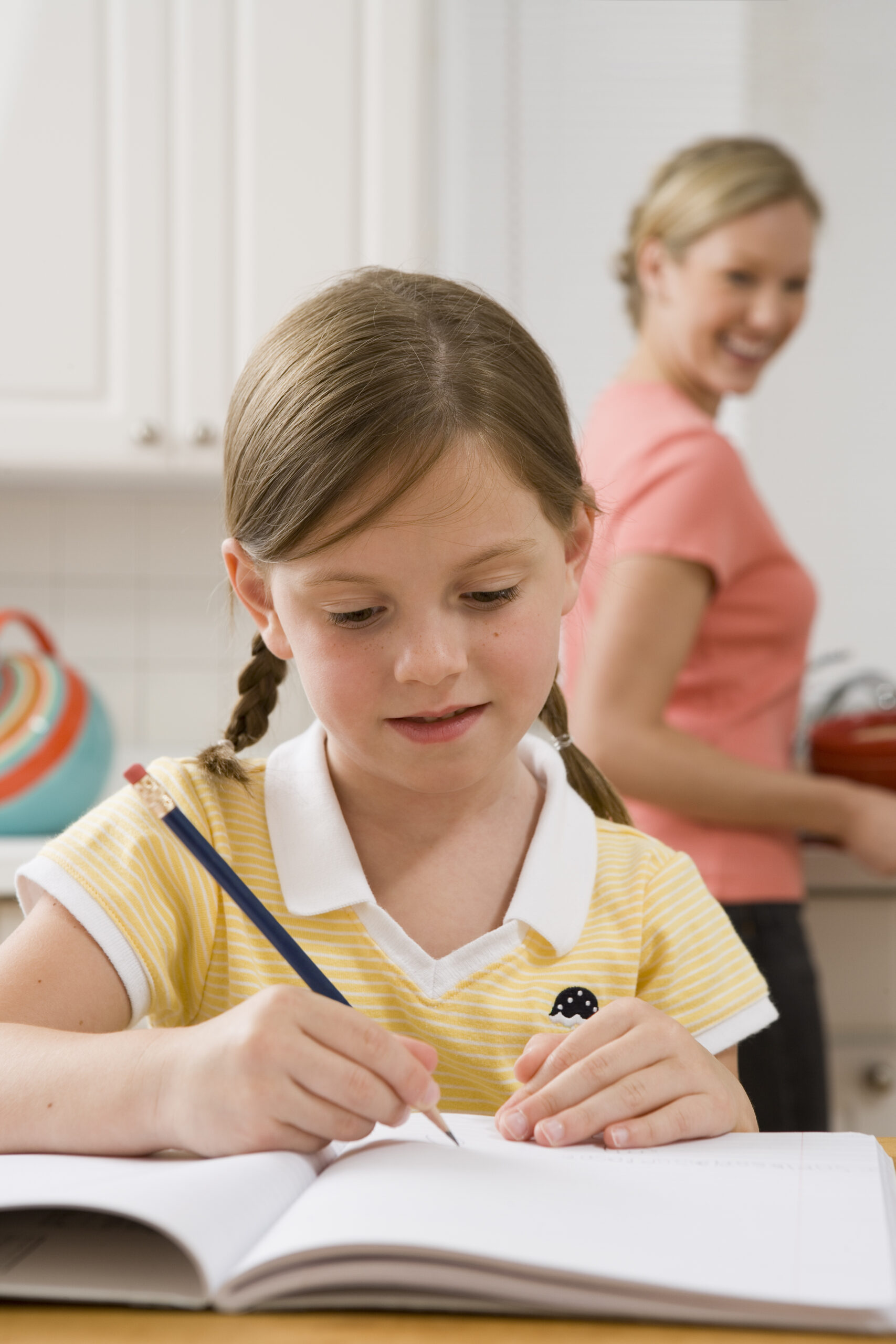 Girl doing homework with mother watching from behind
